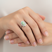 Opal Radiance oval opal and diamond cluster ring worn on hand, showing the colourful play-of-colour and low-profile setting in 18ct yellow gold.