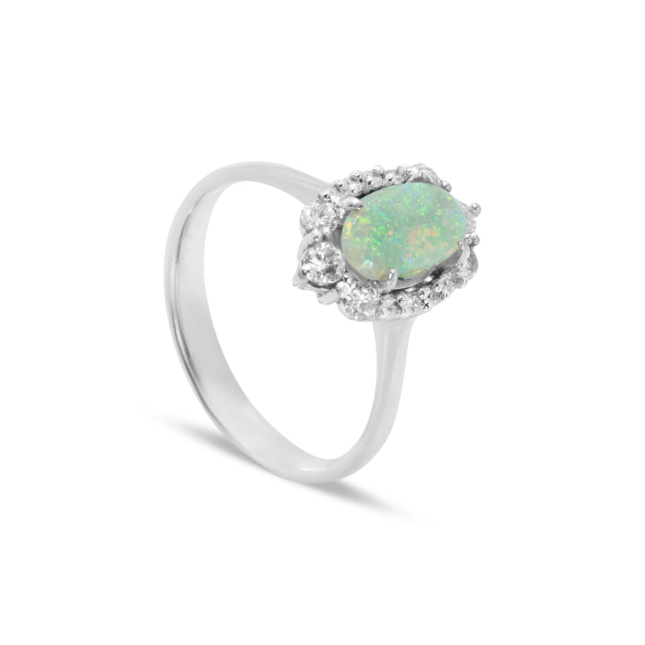 Angled view of 18ct yellow gold oval cabochon opal ring with diamond cluster halo, wire gallery setting, and tapered shank.